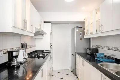 a white kitchen with white cabinets and a sink at Bajada Balta Suites Spacious 3BR in Miraflores Walkable Area in Lima