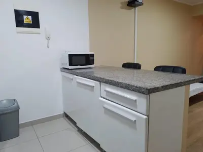 a kitchen with a counter with a microwave and two chairs at Cozy Central Apartment Ideal for Work & Travel in Lima