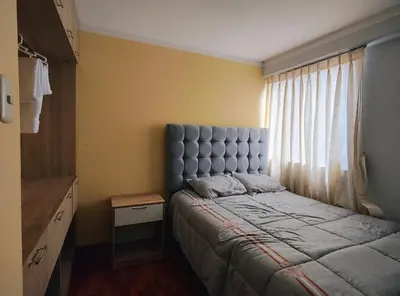 a bedroom with a bed with a blue headboard and a window at Wasin Kusi in Ayacucho