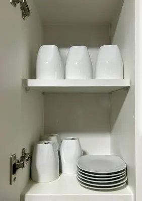 a white shelf with plates and cups and a toilet at Modern room by the sea in Lima
