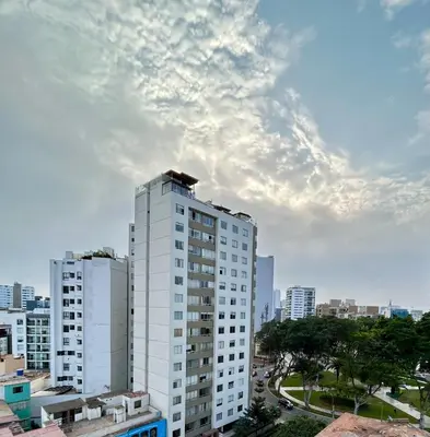 a tall white building in a city under a cloudy sky at Modern room by the sea in Lima