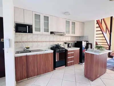 a kitchen with wooden cabinets and a stove top oven at M25 Duplex a media cuadra Embajada de USA in Lima