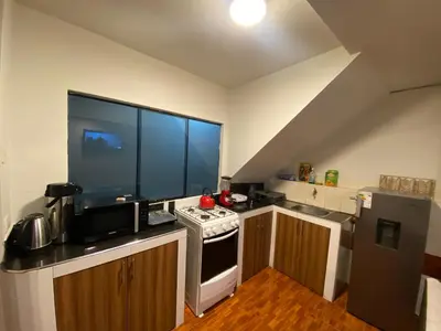 a small kitchen with a stove and a refrigerator at Cozy aparts & rooms in Cusco