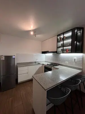 a kitchen with white cabinets and a black refrigerator at Moderno Departamento en Lima - Chorrillos in Lima