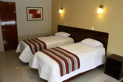 two beds in a hotel room with white sheets at Mauri in Huánuco