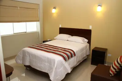 a bedroom with a bed with white sheets and a window at Mauri in Huánuco