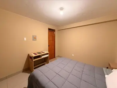 a bedroom with a bed and a table in it at Tres Cruces Private Rooms in Cusco