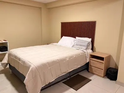 a bedroom with a large bed and a wooden night stand at Tres Cruces Private Rooms in Cusco