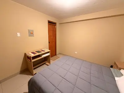 a bedroom with a bed and a small table at Tres Cruces Private Rooms in Cusco