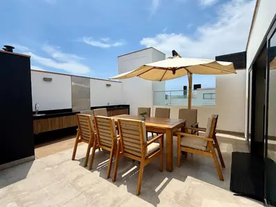 a wooden table with chairs and an umbrella on a balcony at Departamento Graña in Lima
