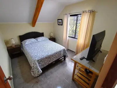 a bedroom with a bed and a flat screen tv at La Casa de ANNI in Oxapampa