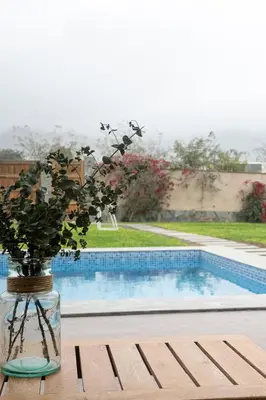 a vase with flowers sitting on a table next to a pool at Casa Cieneguilla in Cieneguilla