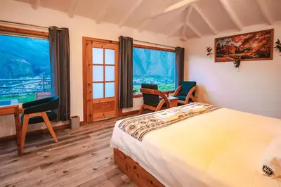 a bedroom with a bed and two chairs and a desk at Tara Vegan Lodge - Sacred Valley in Urubamba