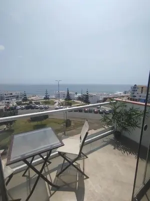 a table and a chair on a balcony with a train at Apartment facing Mirador Analí in Punta Hermosa