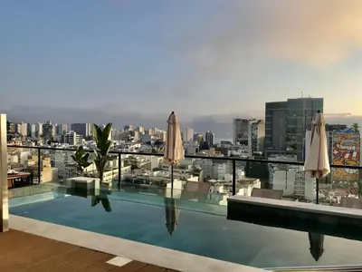 a swimming pool with umbrellas and a city skyline at 2BR Apartment with Pool near Larcomar in Lima