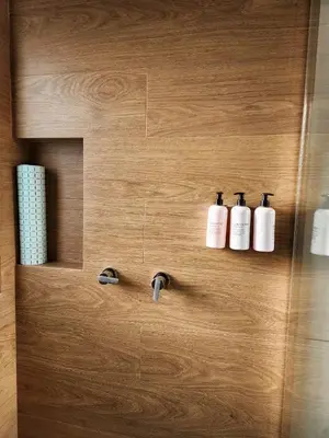 a bathroom with three soap bottles on a wooden wall at Lama Vista Living 302 in Cusco
