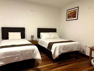two beds in a room with white walls and wooden floors at Cusco - Flor de Loto in Cusco