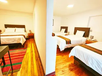 two beds in a room with wooden floors at Cusco - Flor de Loto in Cusco