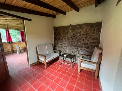 a living room with two chairs and a stone wall at La Casa de Tay in Urubamba