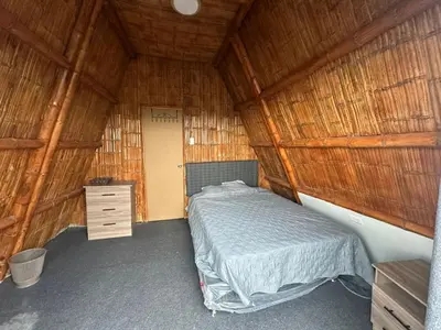 a bedroom with a bed in a straw hut at Cabaña las Palmeras de Chincha