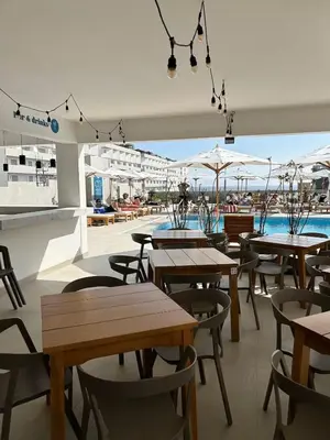 a restaurant with tables and chairs and a pool at Apartamento nuevo en San Bartolo con vista al mar in San Bartolo