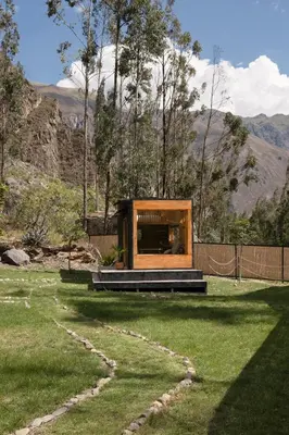 a house with a window in a field of grass at Earth Tones Tiny Homes & Suites in Ollantaytambo