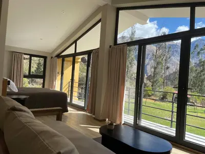 a room with a bed and a large window at Earth Tones Tiny Homes & Suites in Ollantaytambo