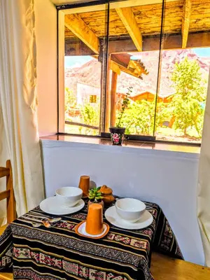 a table with plates and bowls on a table in front of a window at Loft Rústico 03 en Valle Sagrado in Urubamba