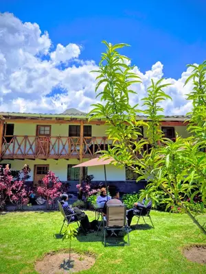 people sitting in chairs under an umbrella in front of a building at Loft Rústico 03 en Valle Sagrado in Urubamba
