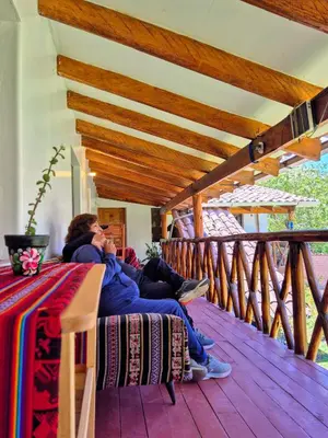 two people sitting on a porch talking on a cell phone at Loft Rústico 03 en Valle Sagrado in Urubamba