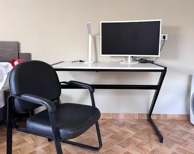 a black desk with a computer monitor and a chair at Peruvian Apartments La Angostura in Ica