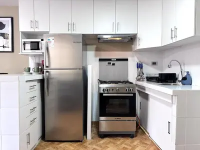 a kitchen with a stainless steel refrigerator and white cabinets at Peruvian Apartments La Angostura in Ica