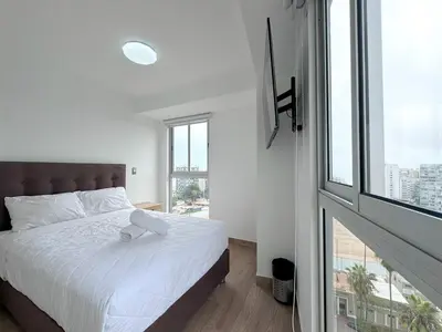 a bedroom with a white bed and a large window at Peruvian Apartments Barranco 1404 in Lima