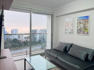 a living room with a couch and a large window at Peruvian Apartments Barranco 1710 in Lima