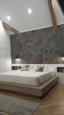 a bedroom with a large bed with a stone wall at Steinhaus - Nature, calm and comfort in Oxapampa