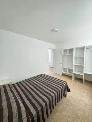 a bedroom with a striped bed and white shelves at Departamento cerca a la playa 202 in Punta Negra