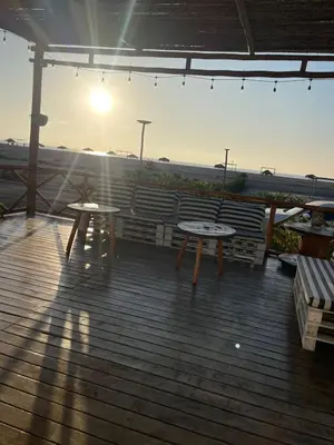 a deck with two tables and a bench on the beach at Refugio 55 Casa de Playa en Chincha, Frente al mar in Chincha Baja