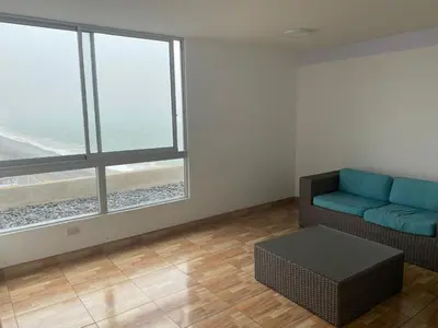 a living room with a couch and a large window at Life is better by the sea in Lima