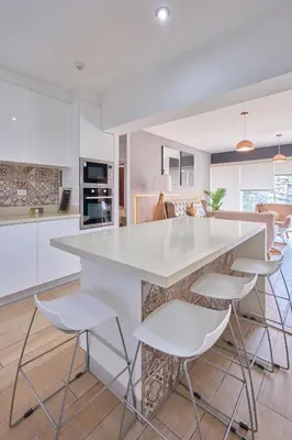 a kitchen with a large white counter and stools at Barranco Bright apartment with Balcony in Lima