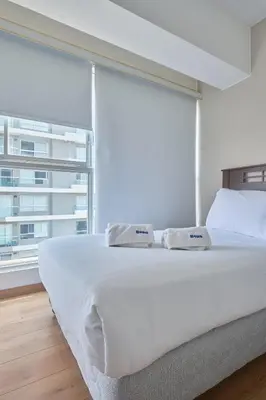 a bedroom with a large white bed with a large window at Barranco Bright apartment with Balcony in Lima