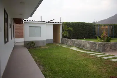 a house with a grassy yard next to a building at Casa de Campo Pachacamac in Pachacamac