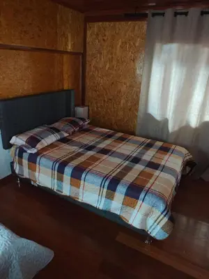 a bed with a plaid blanket and a window at Oxapampa Center Room- habitacion centro in Oxapampa