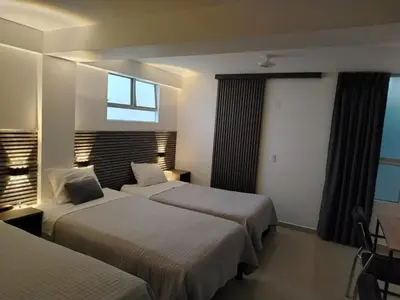 a hotel room with two beds and a window at Hostal Mirador in Pisco