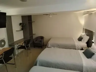 a hotel room with two beds and a desk at Hostal Mirador in Pisco