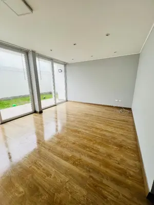 an empty room with wooden floors and large windows at El Derby in Lima