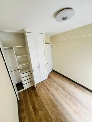 an empty room with white cabinets and wood floors at El Derby in Lima