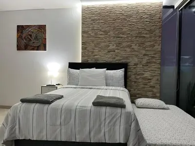 a bedroom with a large bed and a brick wall at Albano Penthouse íntimo piscina y vista al mar in Lima