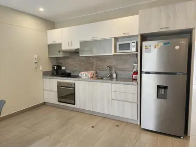 a kitchen with white cabinets and a stainless steel refrigerator at Condominio Ocean Reef Playa Norte San Bartolo in San Bartolo