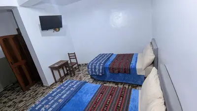 a bedroom with two beds and a tv on the wall at Aguilar Apaza Family in Machu Picchu