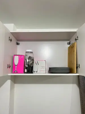 a shelf with plates and a glass of wine at Departamento de un solo ambiente in Lima